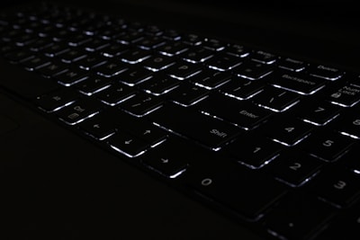 Close-up of a premium keyboard with backlit keys glowing softly in a dark room.