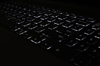 Close-up of a high-quality keyboard with backlit keys glowing softly in a dim room.