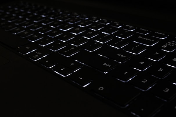 Close-up of a high-quality keyboard with backlit keys glowing softly in a dim room.