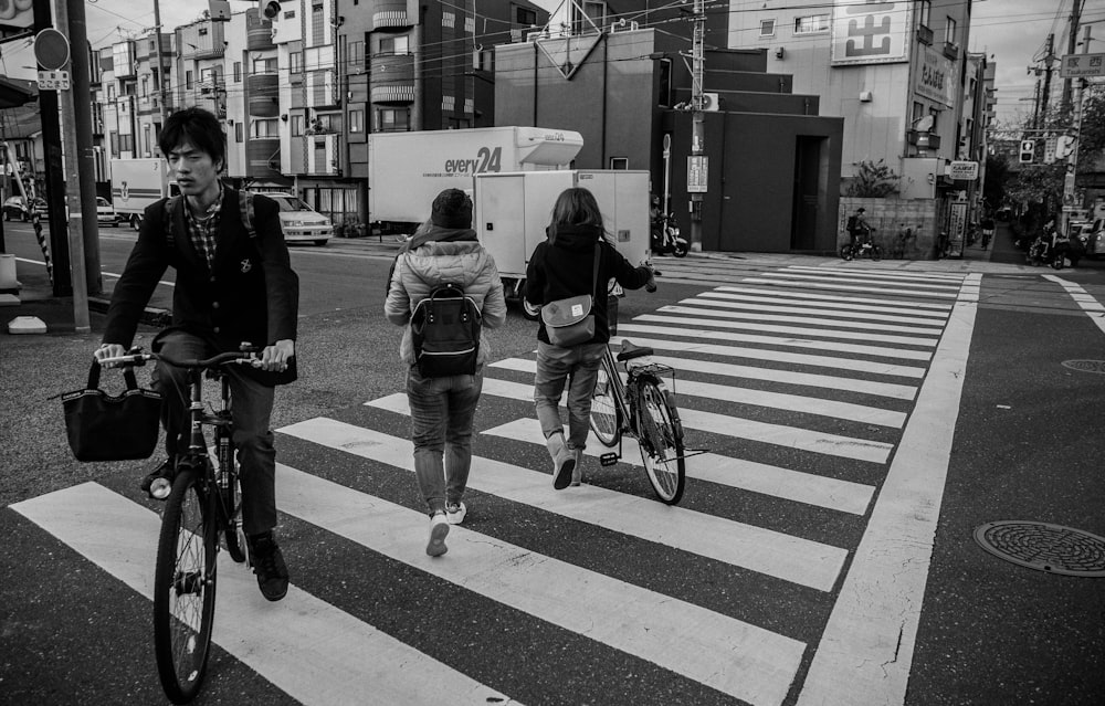 grayscale photo of three person on pedestrian lane