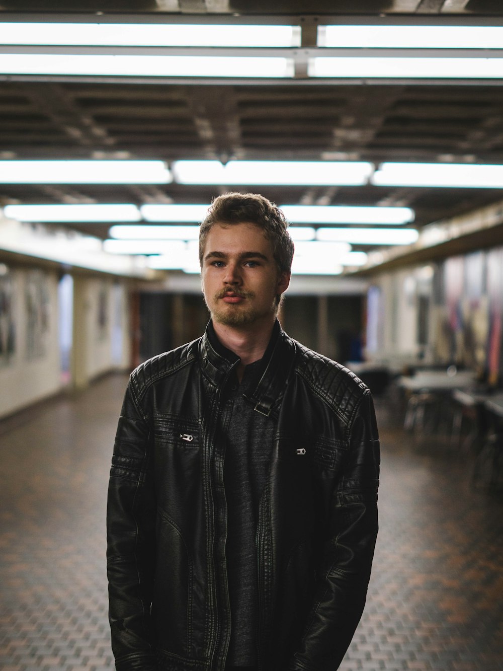 man wearing black leather jacket inside lighted room