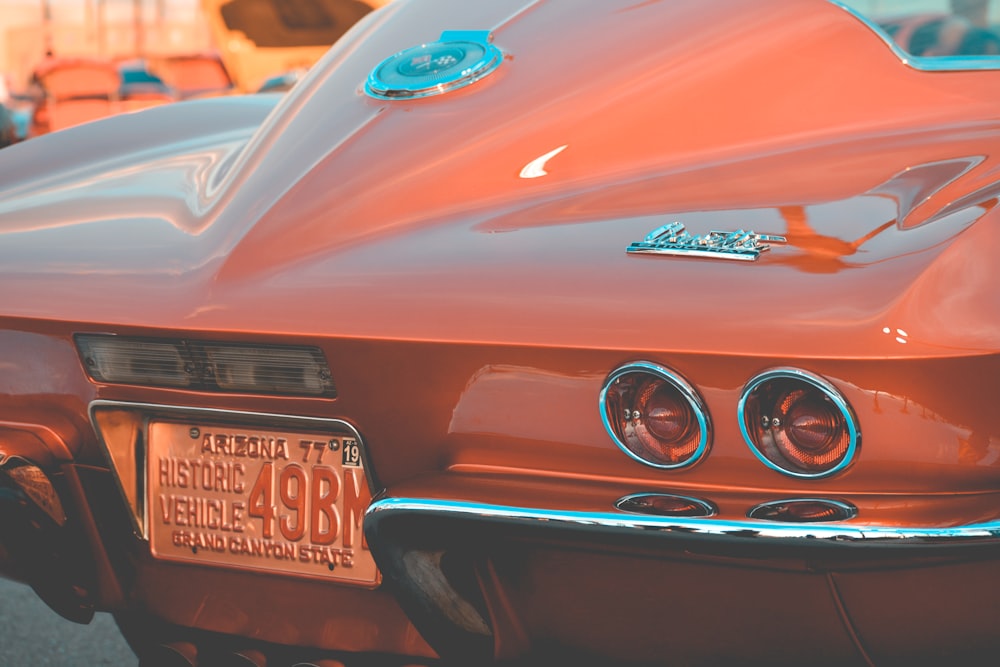 orange sports car rear view on park during daytime