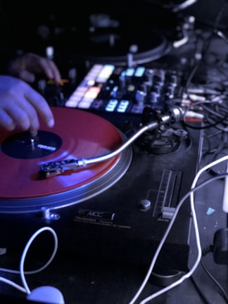 DJ spinning vinyl records with glowing neon red headphones in a dark studio.