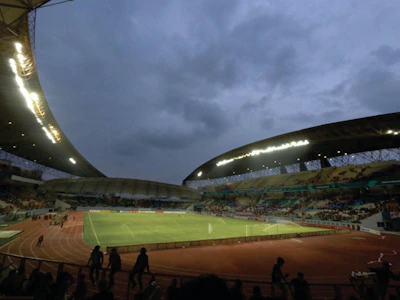 A panoramic view of a packed stadium under bright floodlights during an evening game