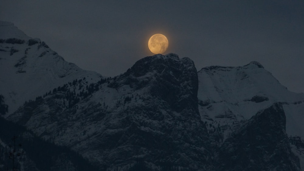 full moon over a snowy mountain top