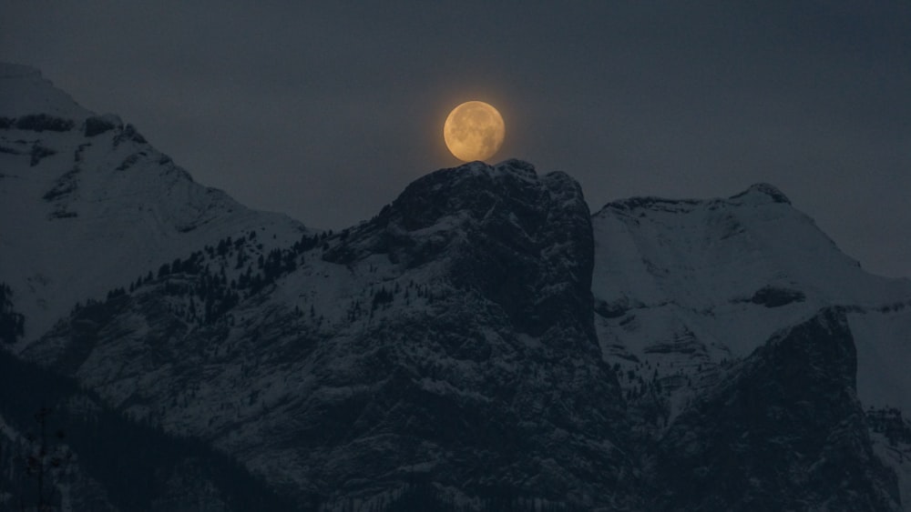 Vollmond über einem verschneiten Berggipfel