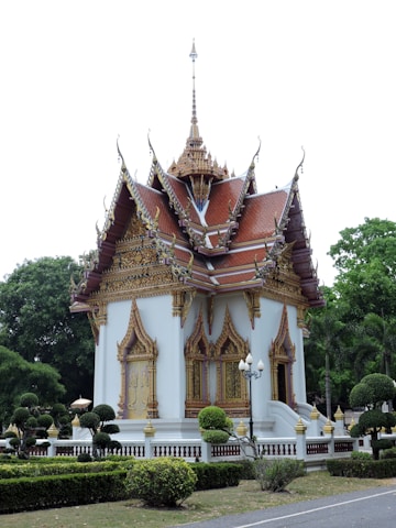 A traditional Thai temple with intricate architecture surrounded by lush greenery.