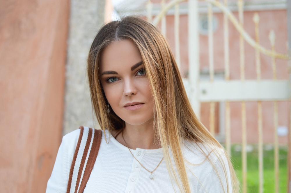 woman wearing white button-up top near white gate