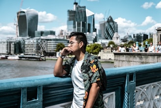 man wearing black and yellow floral collared shirt leaning on railing