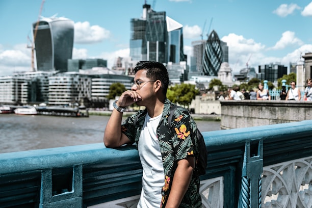 man wearing black and yellow floral collared shirt leaning on railing