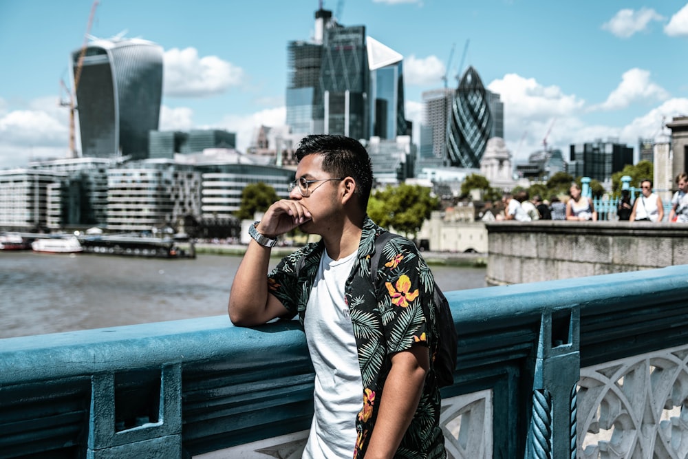 man wearing black and yellow floral collared shirt leaning on railing