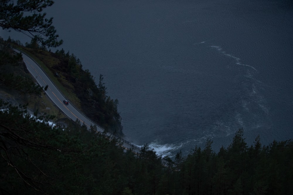 a car driving down a road next to a body of water