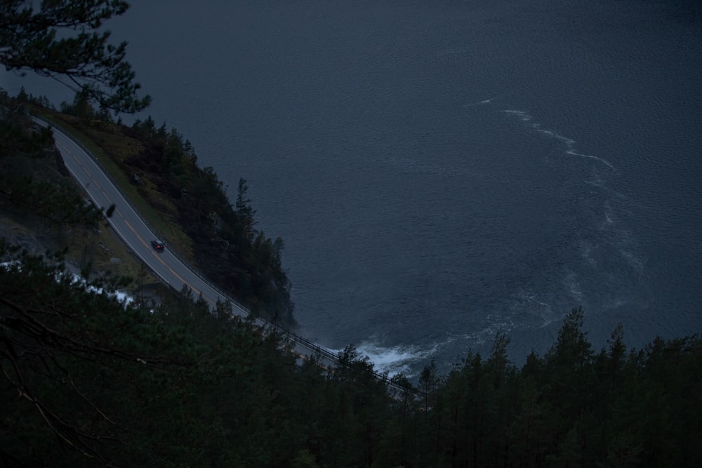 une voiture roulant sur une route à côté d’un plan d’eau