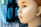A mannequin head with detailed facial features and brown hair is in profile view. The background consists of out-of-focus fabric or clothing with blue and black patterns.