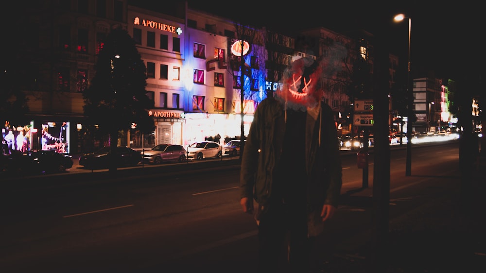 man wearing red and yellow mask beside road during nighttime