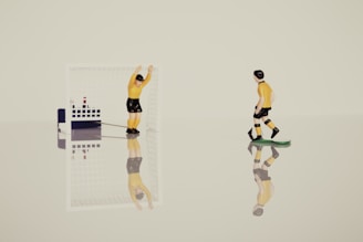 Two small soccer player figurines are positioned on a reflective surface. One is standing inside a miniature goal holding onto the crossbar, and the other seems to be walking on a green base. Their reflections are visible below them.