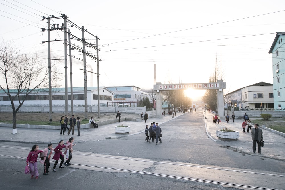 les gens qui marchent, traversent et se tiennent debout dans les rues près des bâtiments ;