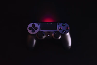 Futuristic neon-lit game controller icon glowing against a dark background.