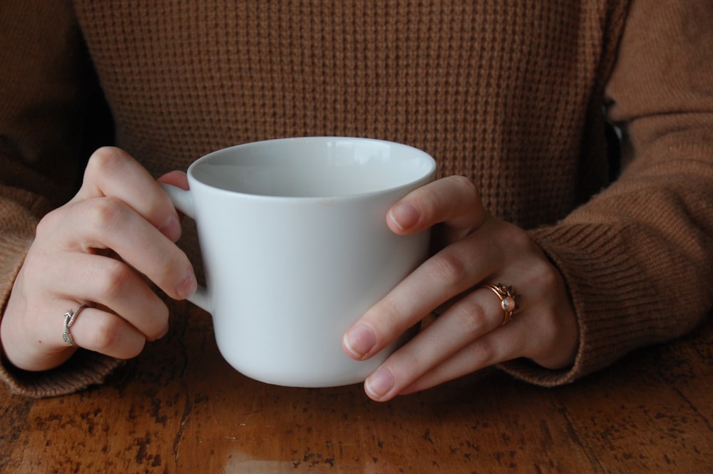 person holding white mug