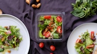 An array of healthy salads arranged on a wooden table.