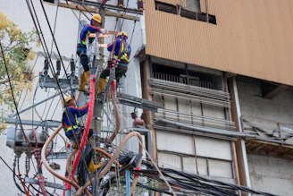 group of people fixing the wires on post