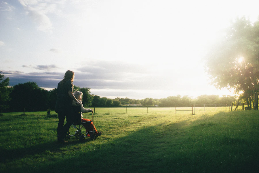 A caregiver walking outdoors beside a senior woman in Lawrence