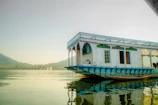 A beautifully decorated wooden houseboat floating serenely on Dal Lake under a morning sky
