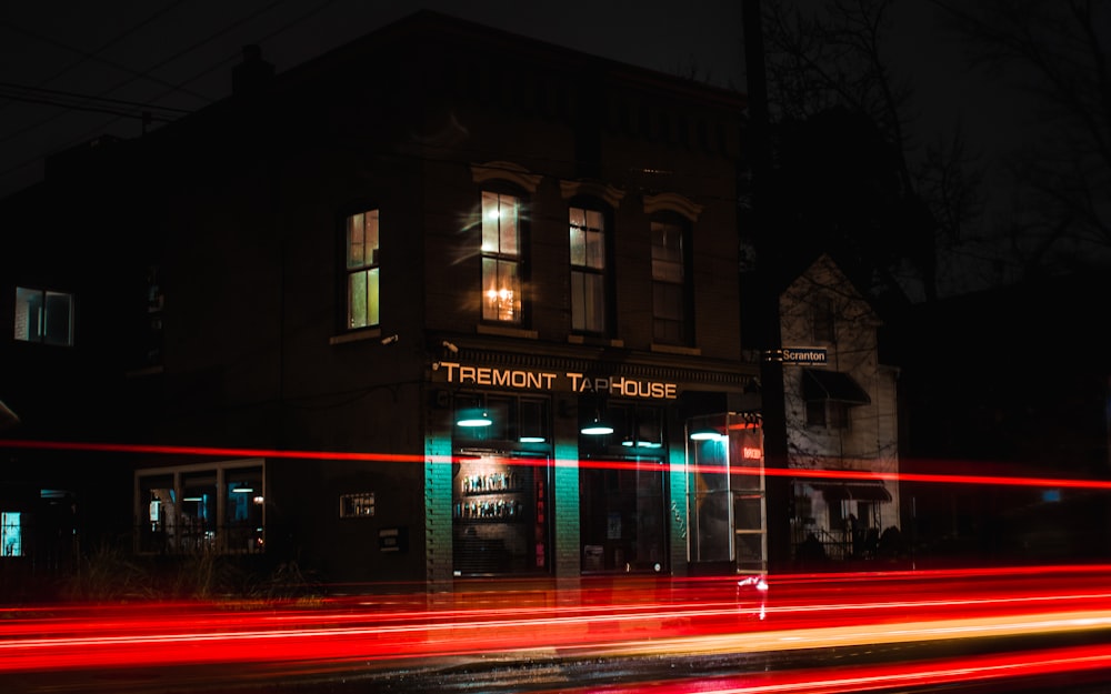 time-lapse photography of passing vehicle beside brown concrete building during nigth