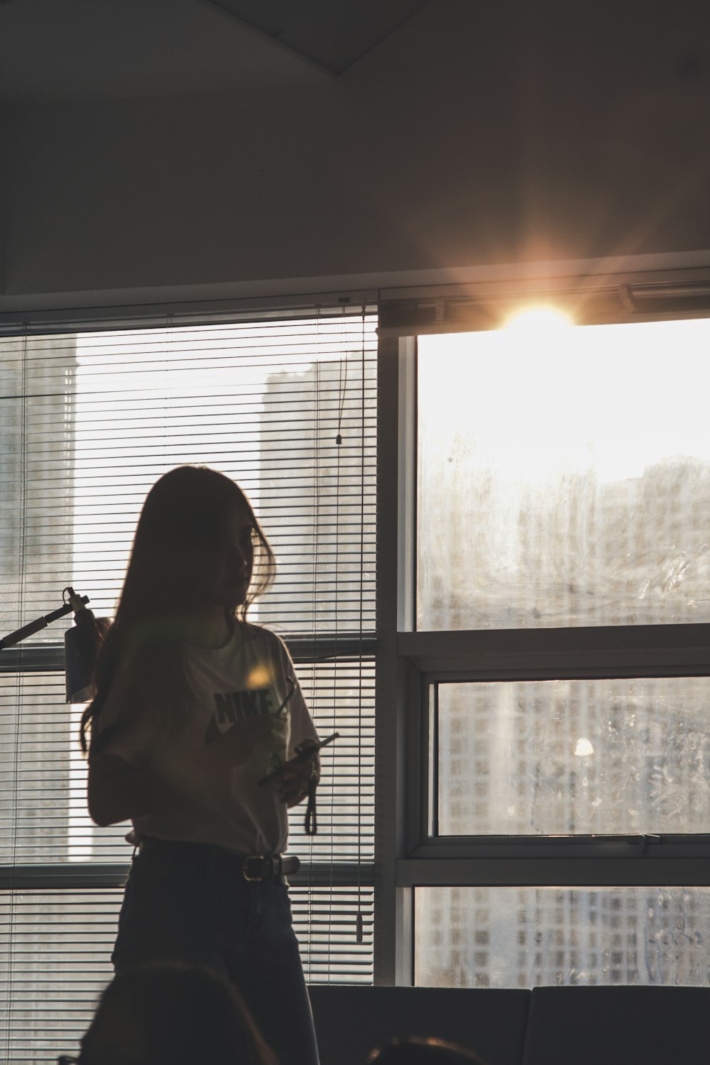 silhouette photography of woman standing by the window during golden hour