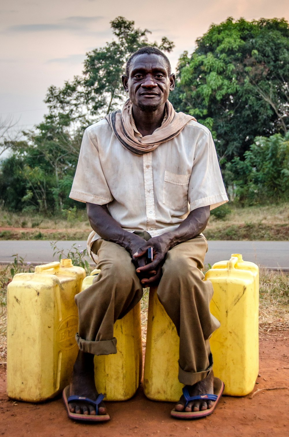 Hombre sentado en recipientes de plástico amarillos