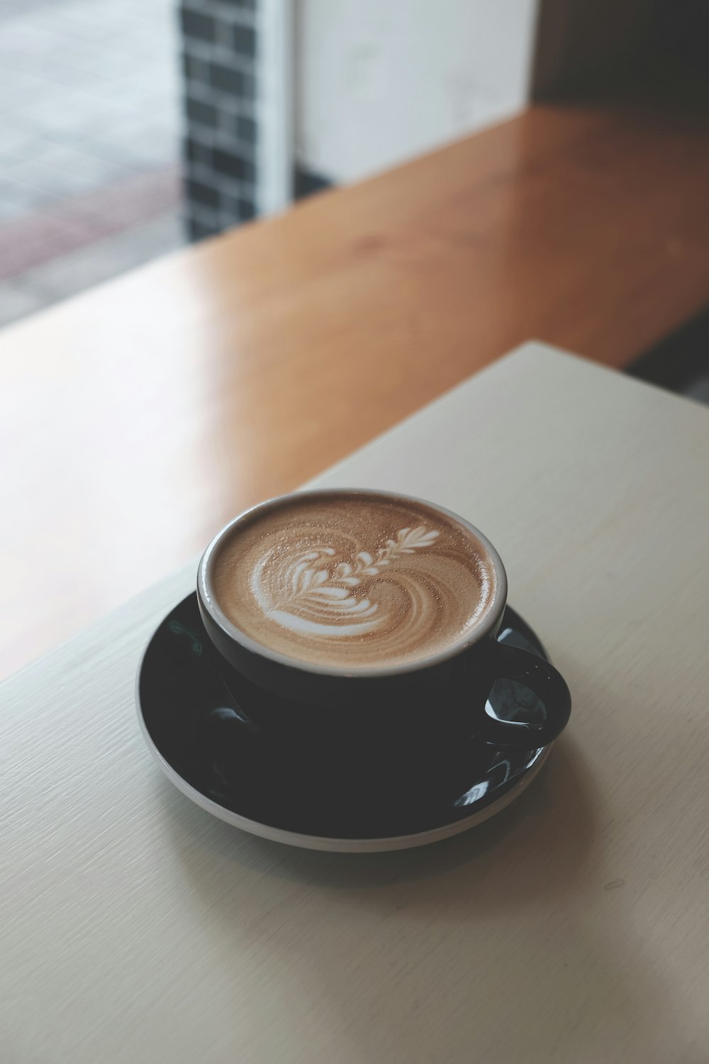 black ceramic teacup with saucer on white wooden table