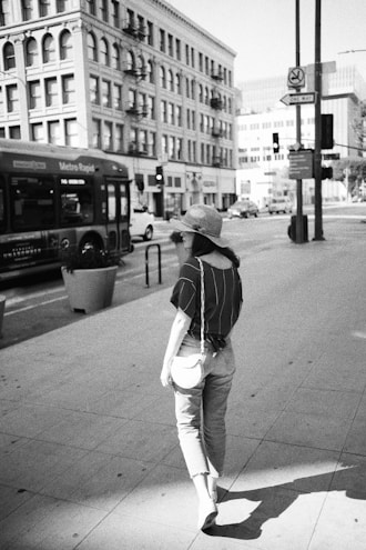 A woman carrying a tote bag while walking in a city.