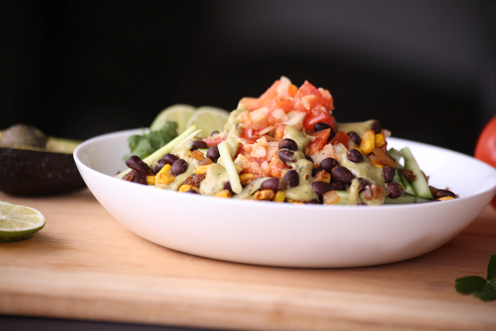 Bowl with black beans, roasted corn, diced tomato, and avocado crema