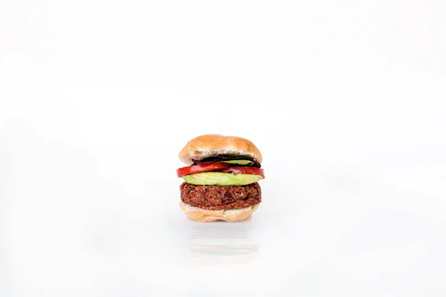 A vibrant burger topped with avocado and spicy sauce, ready to eat.