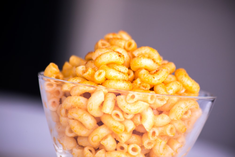 Fresh ingredients for vegan mac and cheese recipe - raw cashews, nutritional yeast, garlic, lemon, and pasta on a wooden table