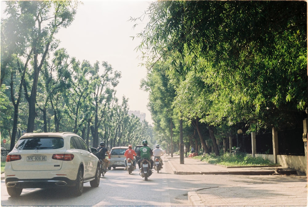 SUV branco e motocicleta preta na estrada ao lado de árvores verdes