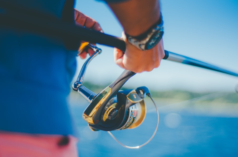 person holding black fishing rod with fishing reel