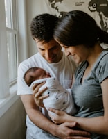 woman holding baby beside man smiling