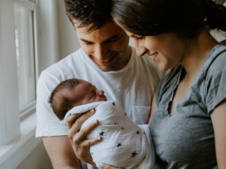 woman holding baby beside man smiling