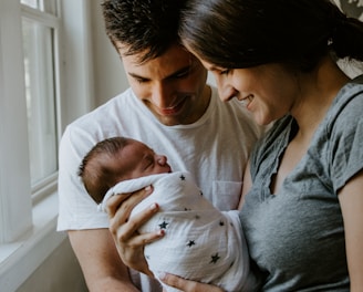 woman holding baby beside man smiling