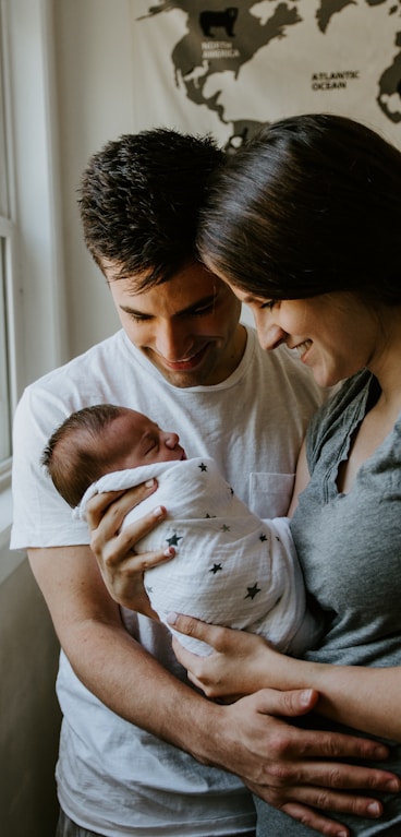 woman holding baby beside man smiling