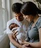 woman holding baby beside man smiling