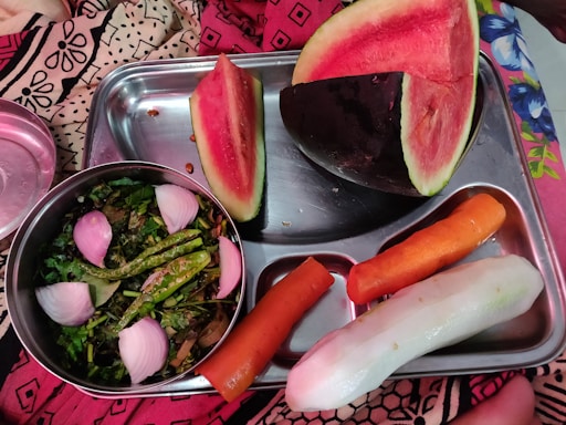 A colorful tray with a balanced meal including vegetables, fruit, and a small sandwich for children.