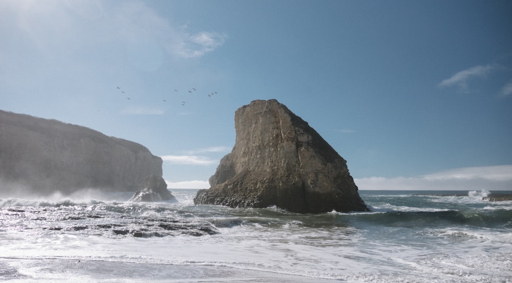 seagulls flying in formation over brown butte in beach