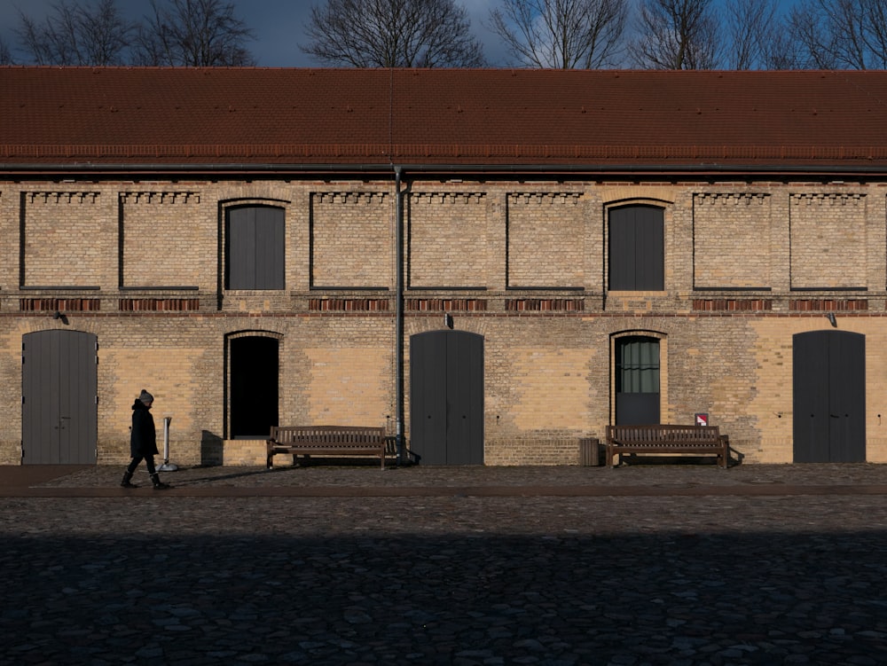 person walking beside concrete building during daytime