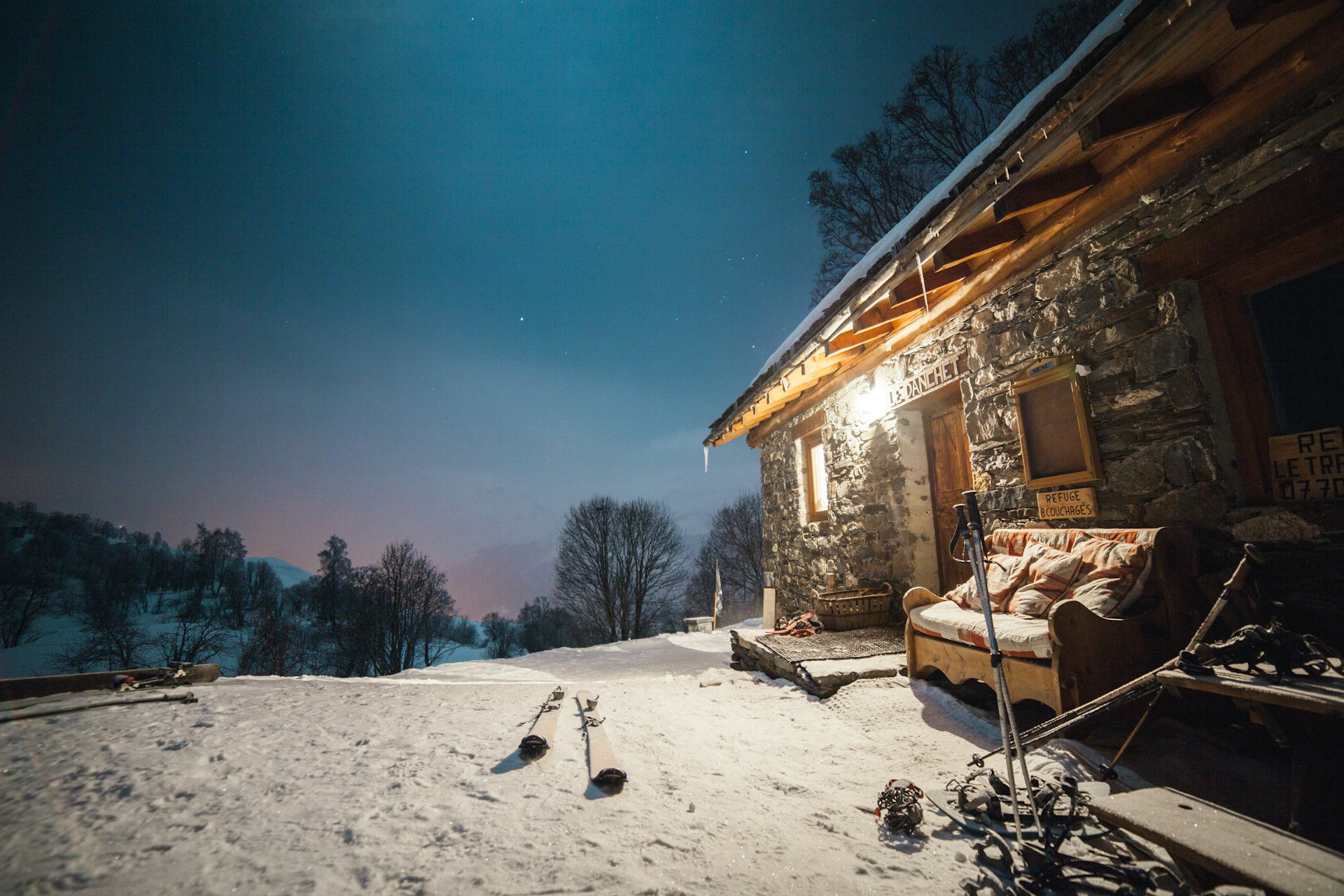 Stone-and-timber custom home lit from within on a winter evening