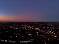 A panoramic view of a city skyline at dusk with illuminated buildings.
