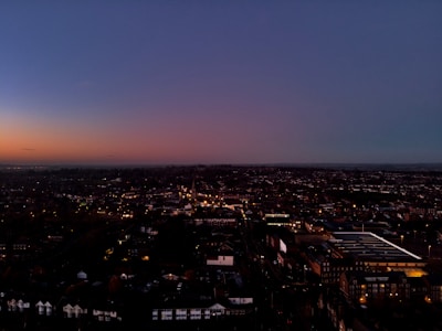 A panoramic view of a city skyline at dusk with illuminated buildings.