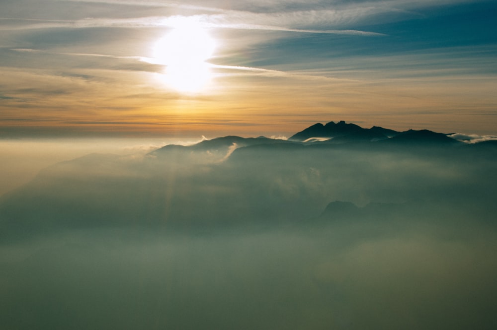 grey clouds covering the mountain terrain at sunset