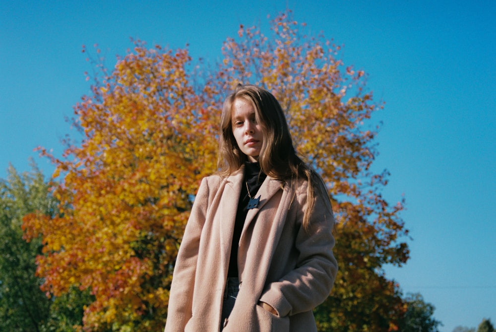 woman wearing brown jacket near brown leafed tree